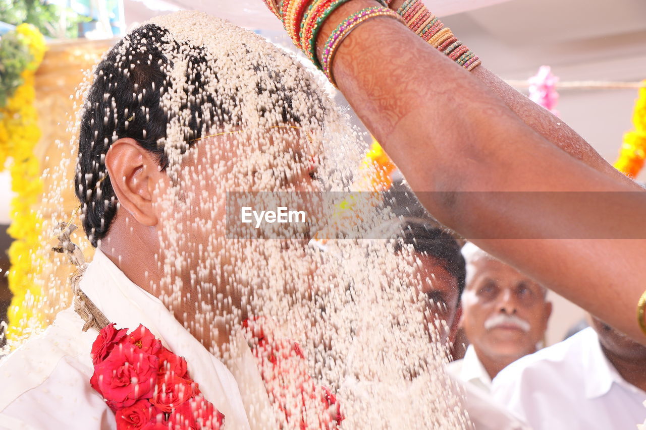 Cropped hands of bride pouring food on groom