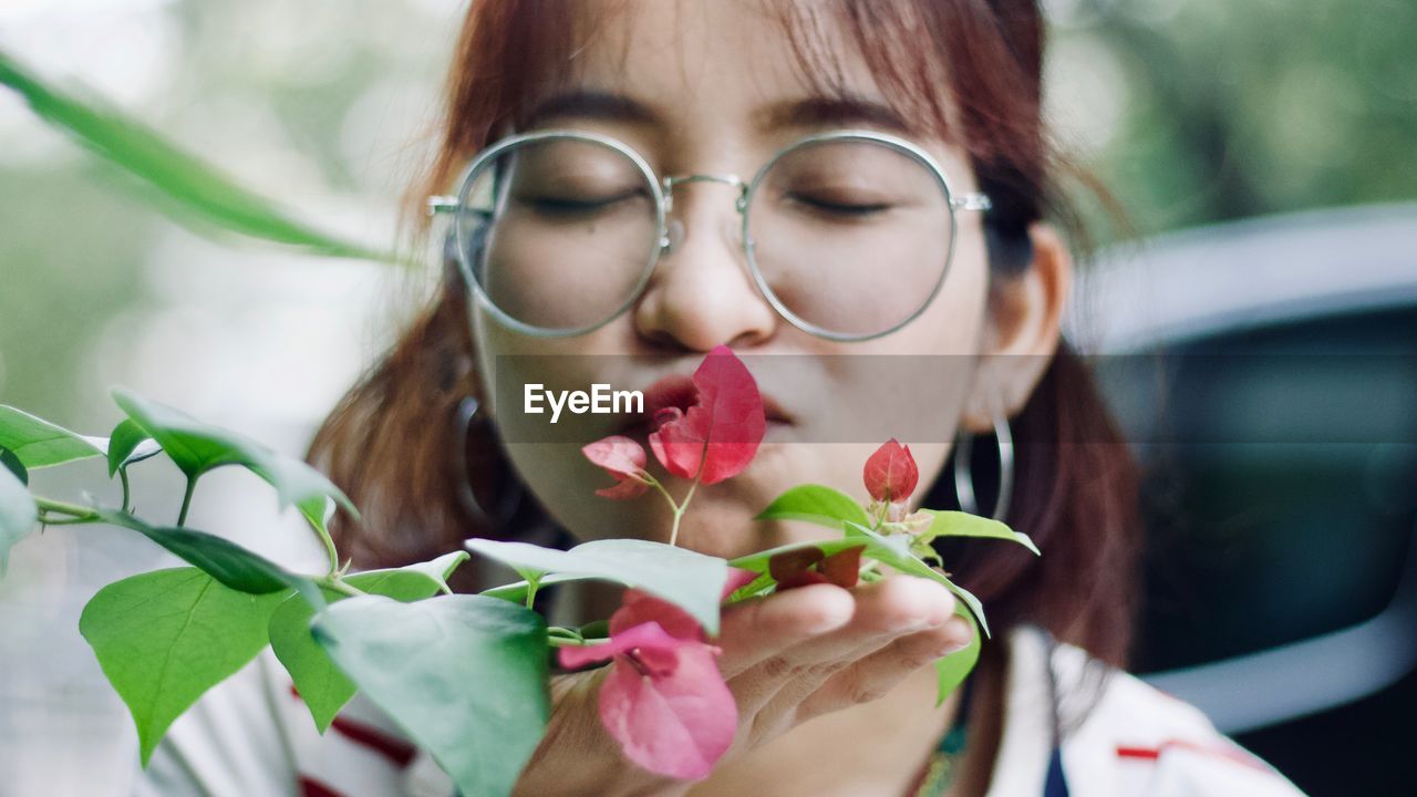 Close-up of young woman kissing leaves blooming outdoors