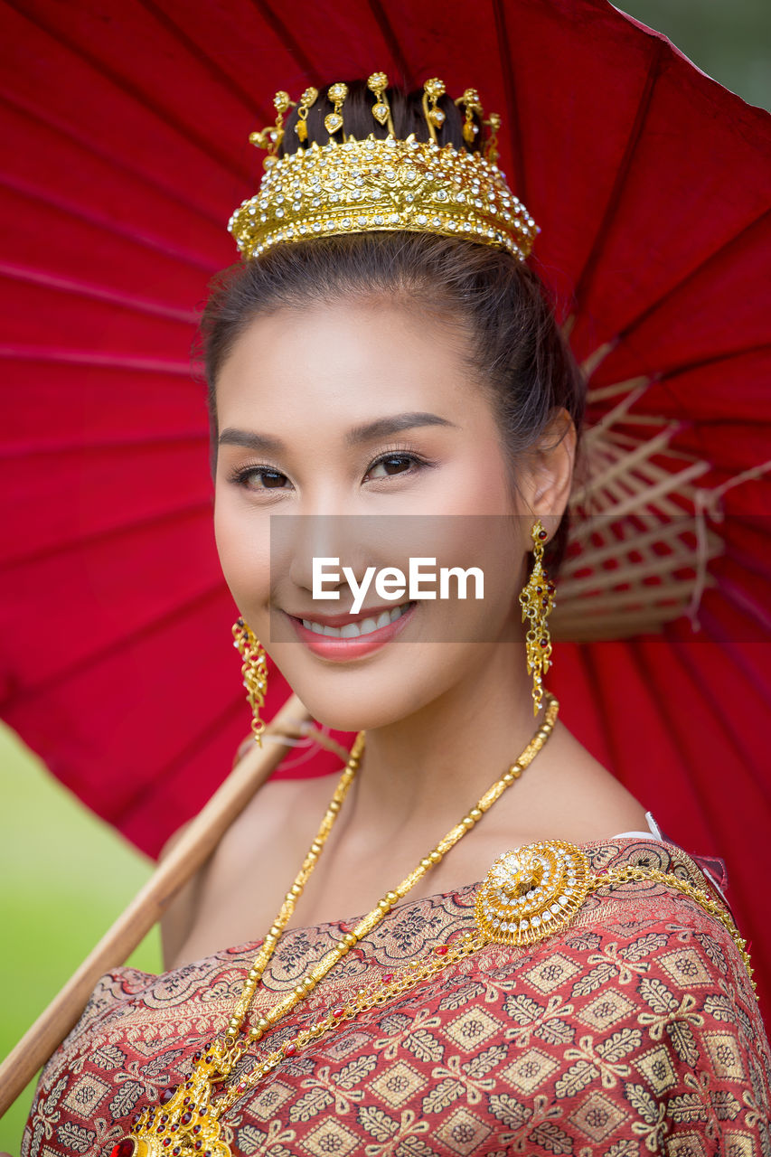 Portrait of smiling woman in traditional clothing with umbrella