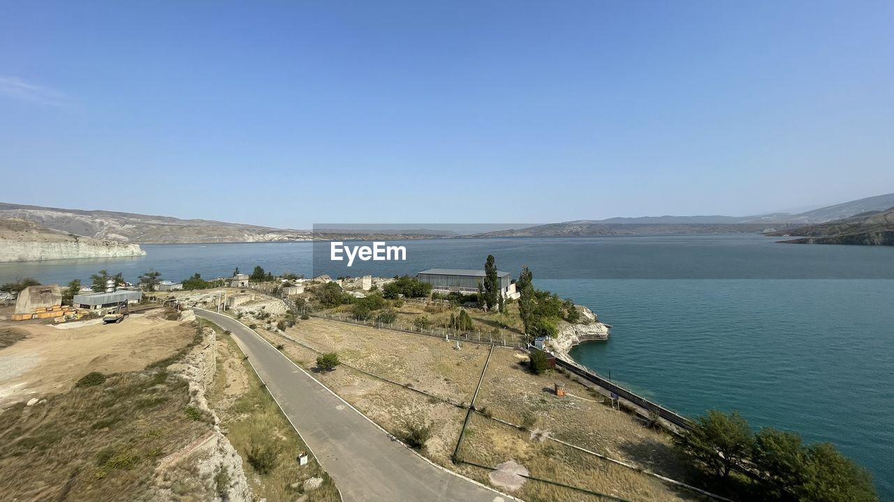 water, coast, sky, sea, nature, scenics - nature, land, reservoir, beauty in nature, clear sky, beach, shore, day, bay, travel destinations, travel, body of water, mountain, transportation, landscape, environment, tranquility, blue, tranquil scene, vacation, no people, architecture, coastline, sunny, outdoors, tourism, ocean, high angle view, non-urban scene, terrain, cliff, built structure, cove, copy space, sunlight, holiday, road, idyllic, trip