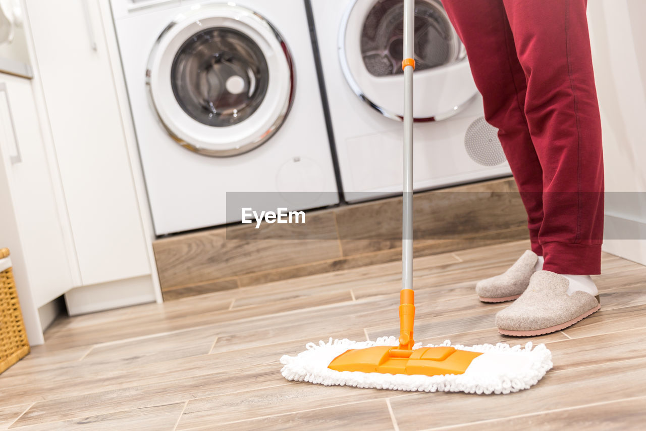 Low section of person cleaning floor