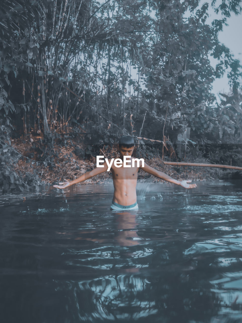 Shirtless man standing in lake