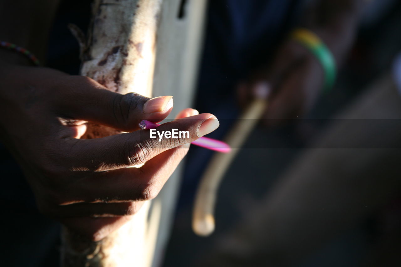 Close-up of hand holding pen by wall