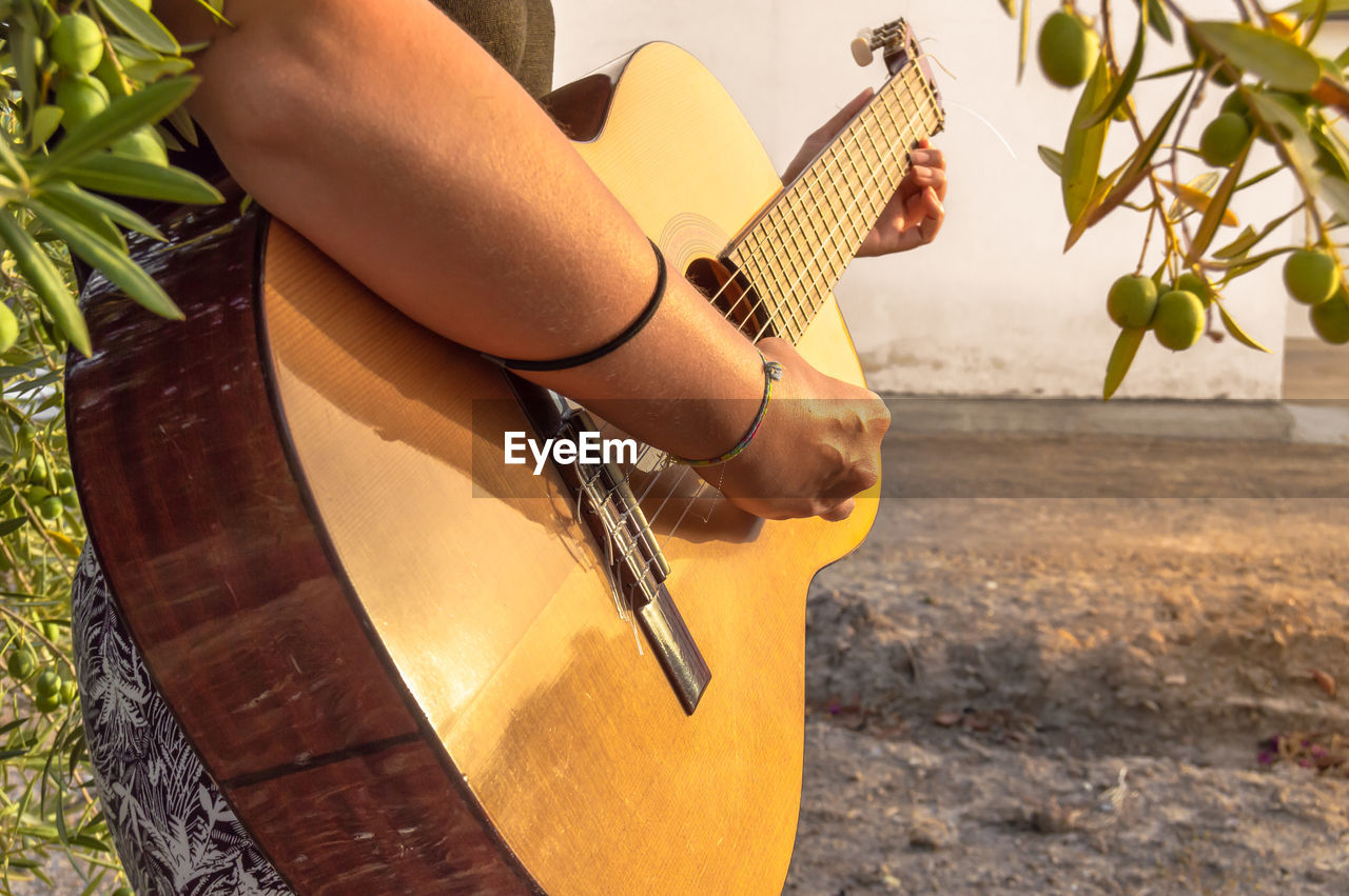 Midsection of woman playing guitar