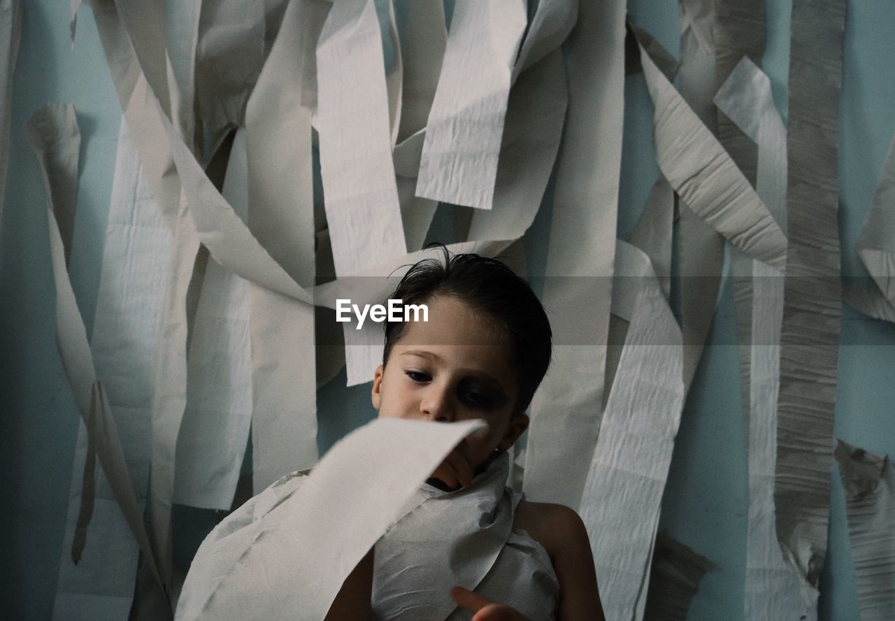 Boy wrapped in toilet paper standing at home