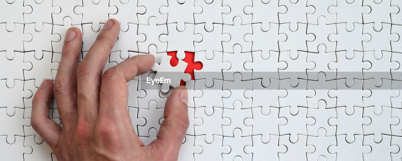 Close-up of hand arranging jigsaw puzzle