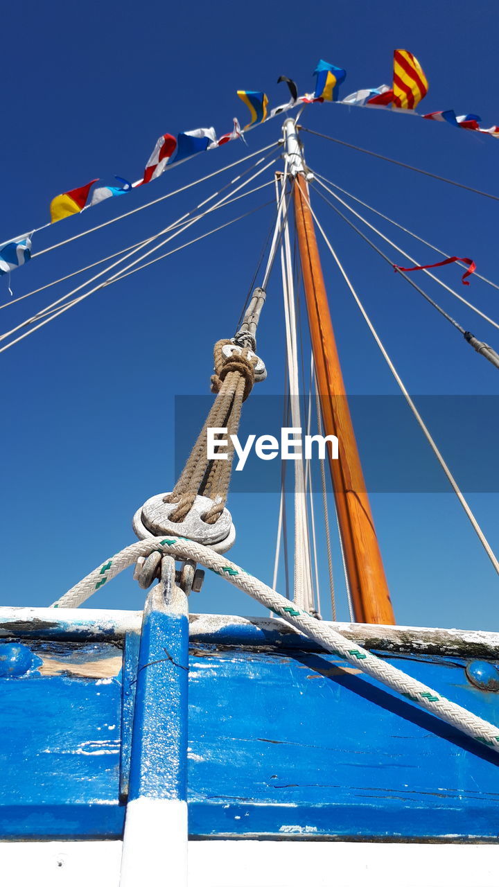 Low angle view of sailboat against blue sky