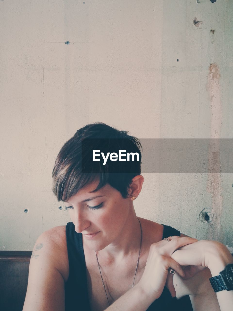 Young woman looking down while sitting in house