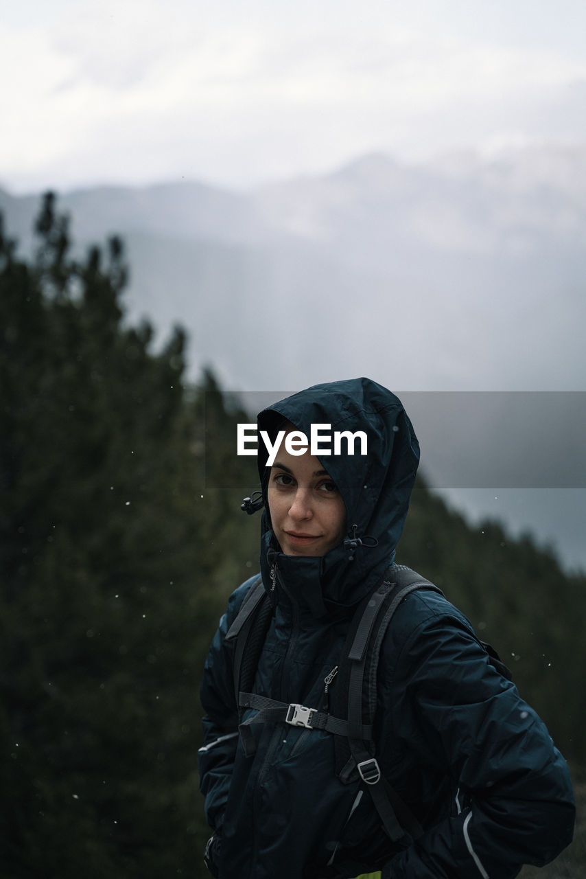 Portrait of a woman standing against forest and sky