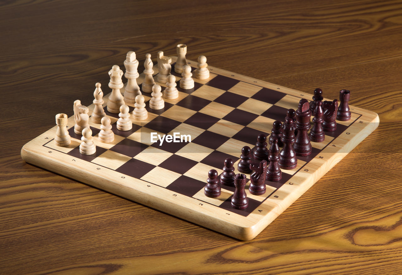 High angle view of chess pieces on wooden table