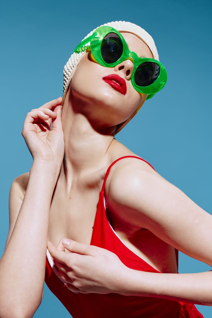 portrait of young woman wearing sunglasses against blue background