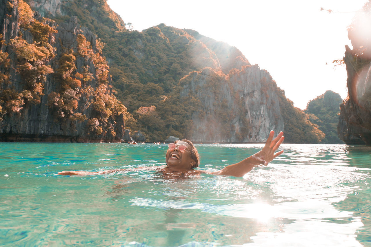 Young man enjoying in sea against mountains