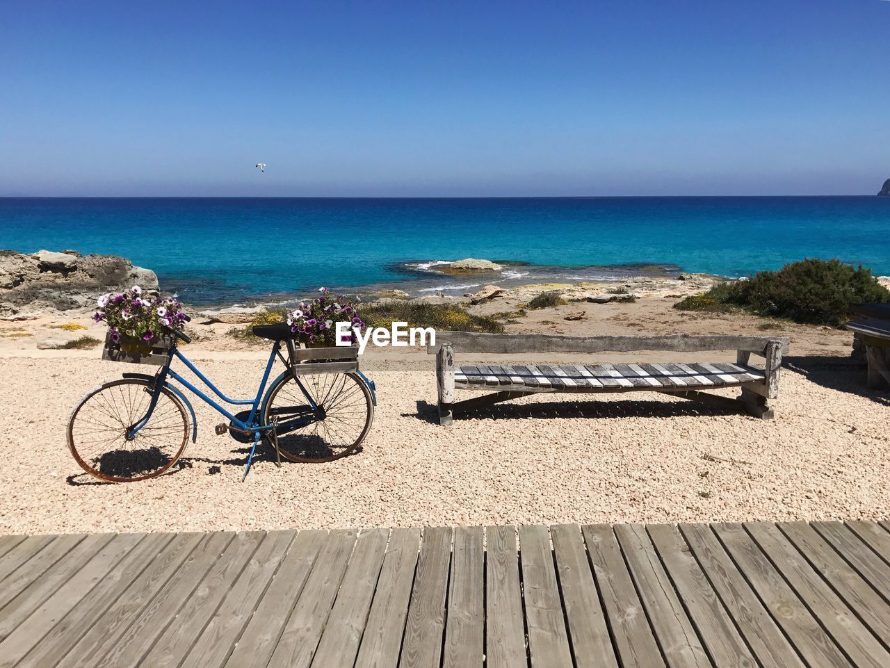 BICYCLES ON BEACH AGAINST SKY