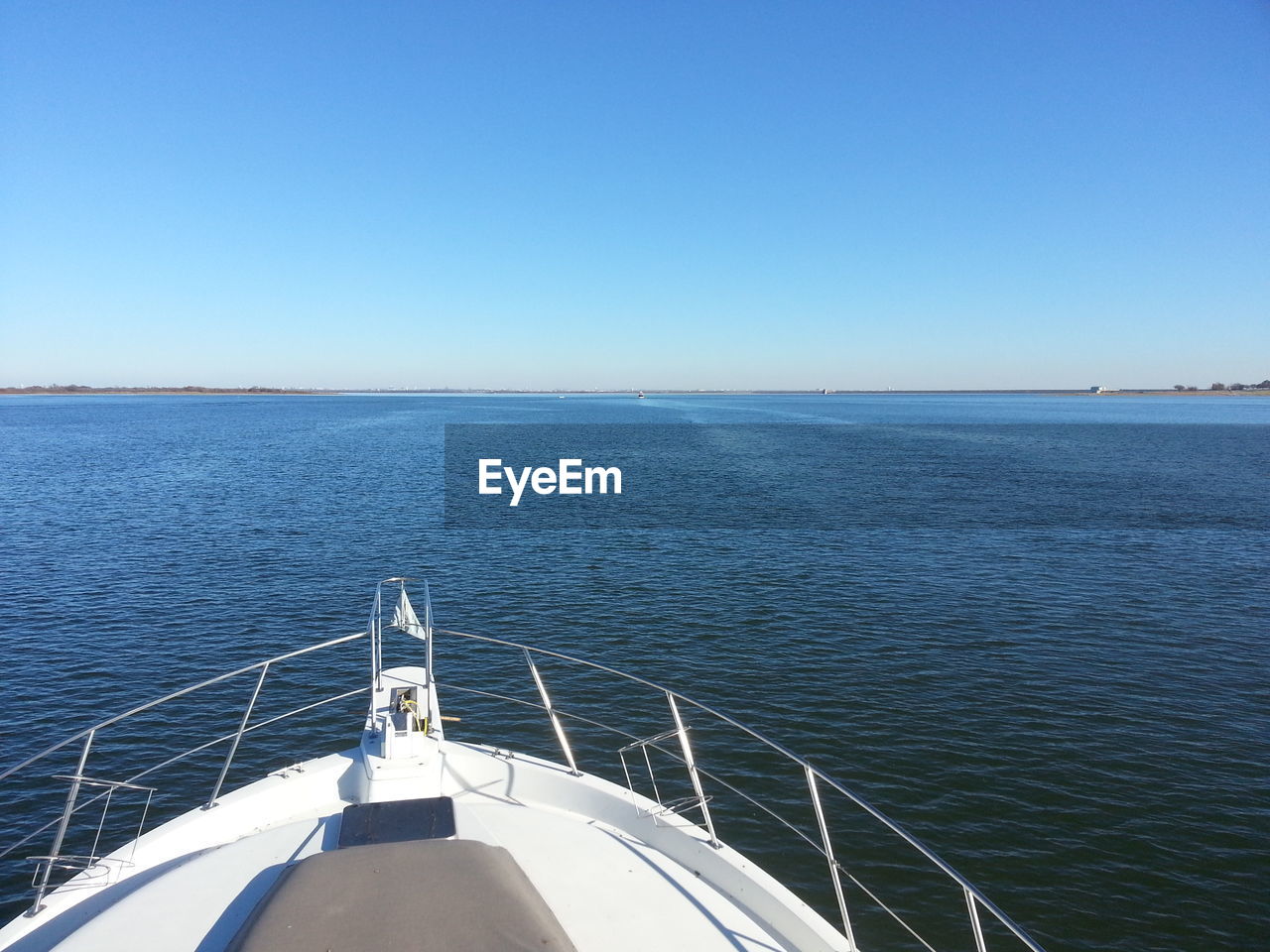 Boat sailing on sea against clear blue sky