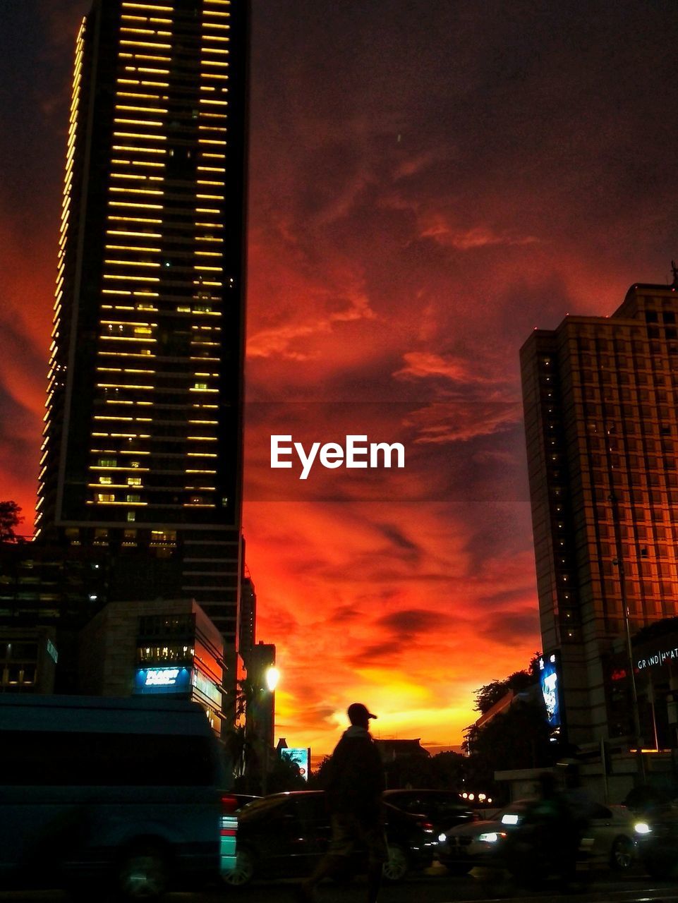 LOW ANGLE VIEW OF ILLUMINATED SKYSCRAPERS AGAINST SKY AT SUNSET