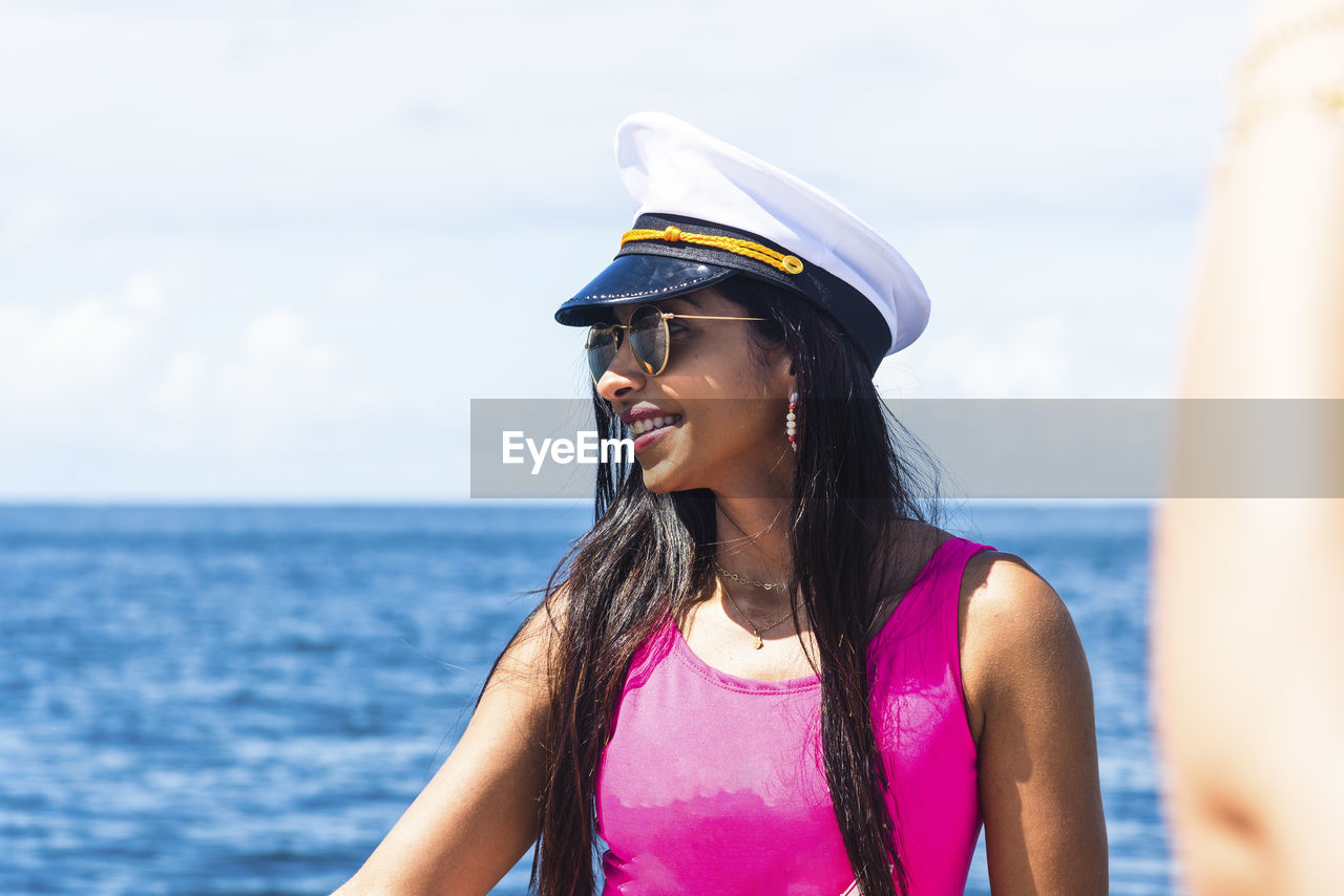 A woman on top of a boat against the sea in the background. 