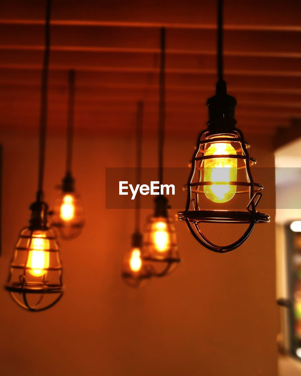 Close-up of illuminated light bulbs hanging from ceiling