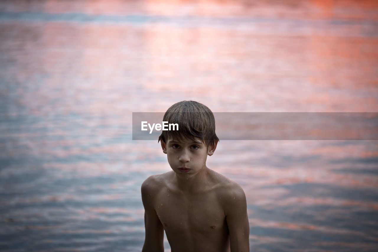 Boy by lake at sunset