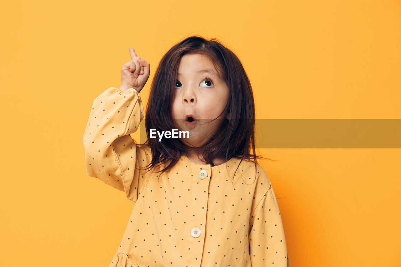 Girl pointing against yellow background