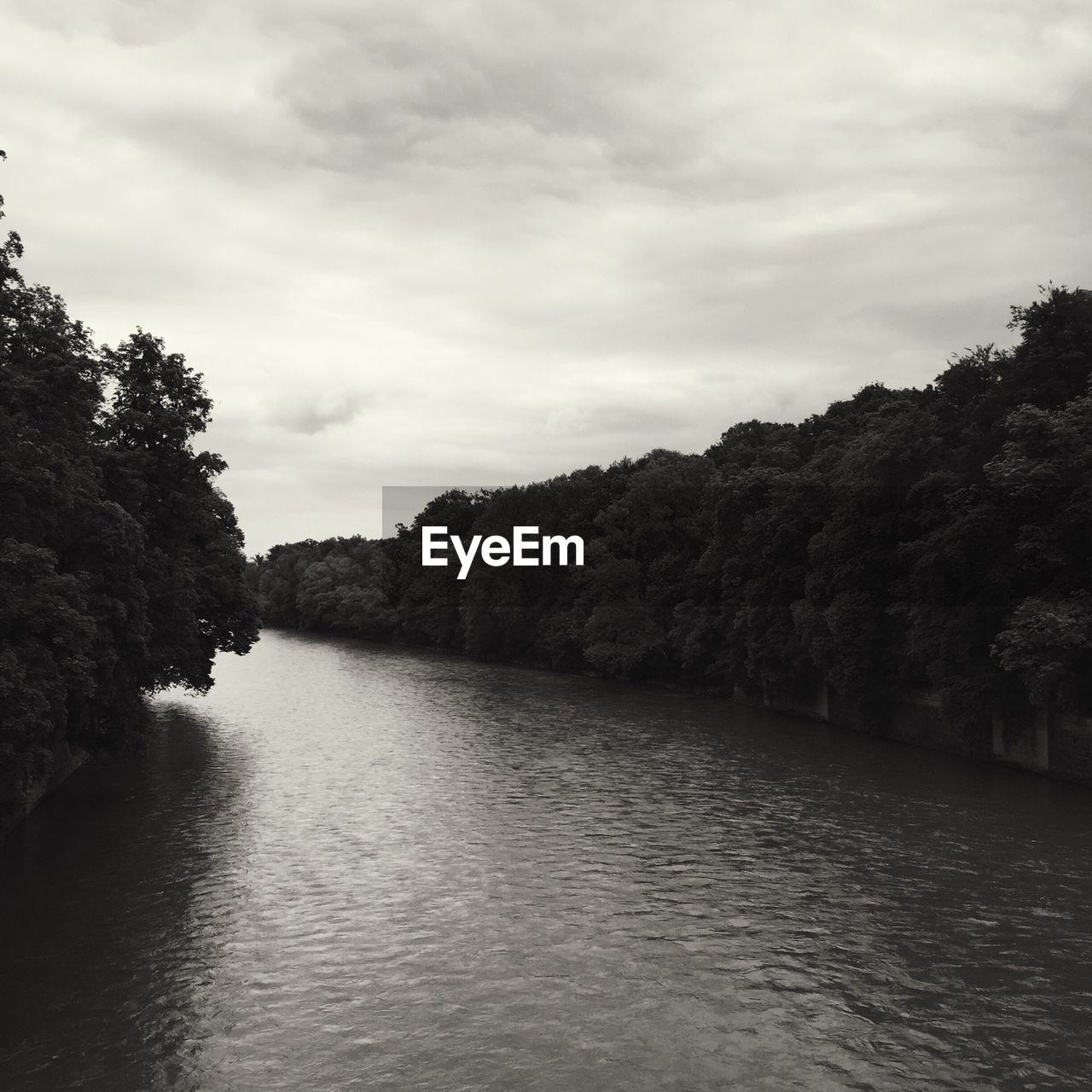 Scenic view of river amidst trees against cloudy sky