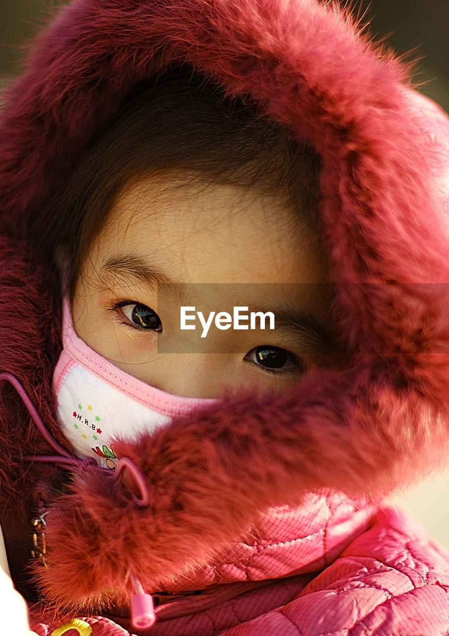 Close-up portrait of cute girl wearing pink hooded jacket