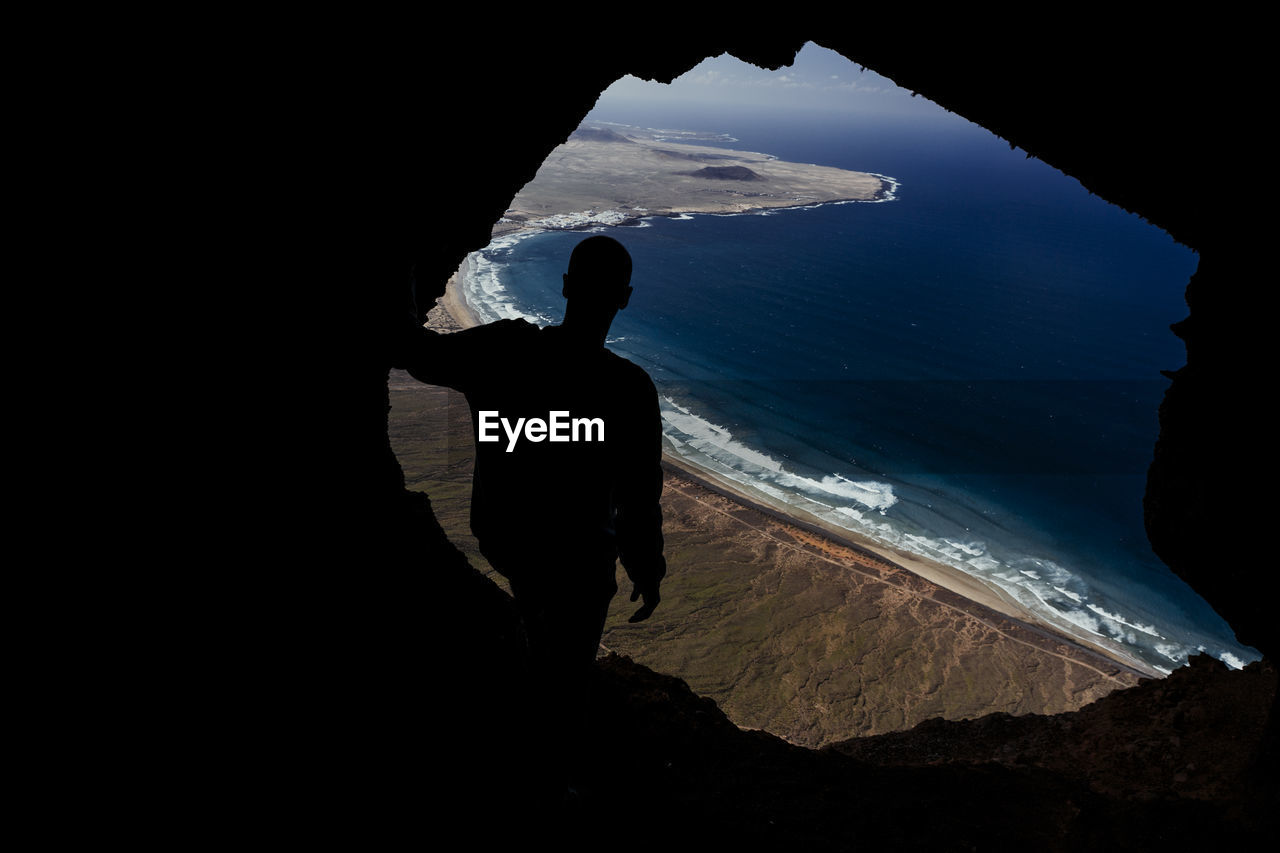 Silhouette of a man from cave on the famara cliff in lanzarote, spain