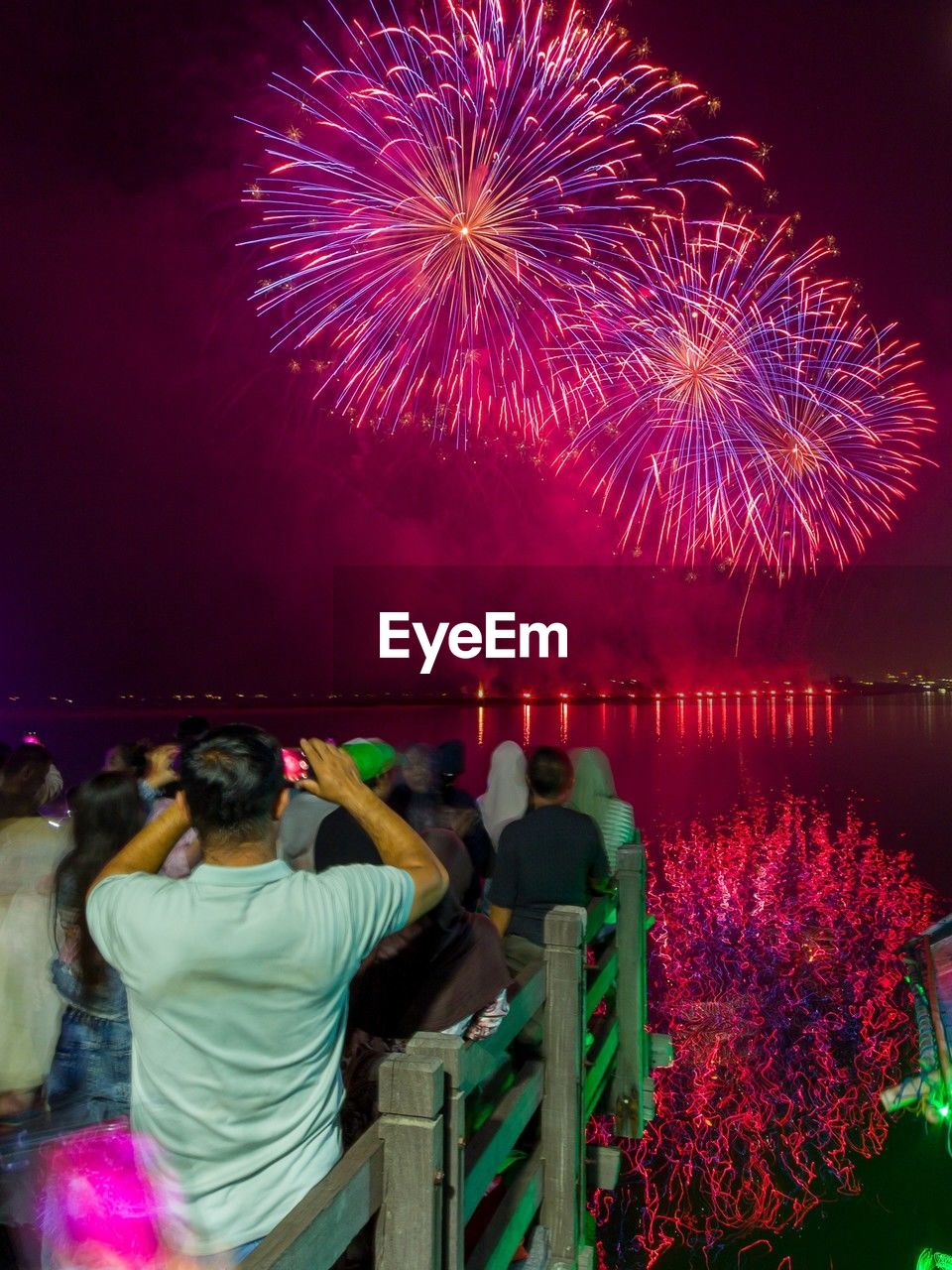 Rear view of woman standing by firework display at night