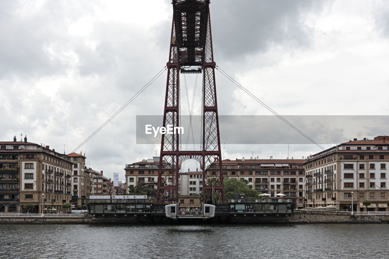 Bridge over river in city against sky