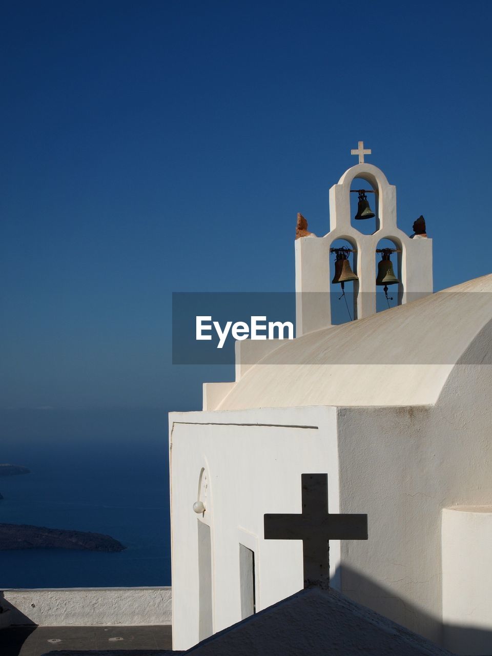 Building by sea against clear blue sky