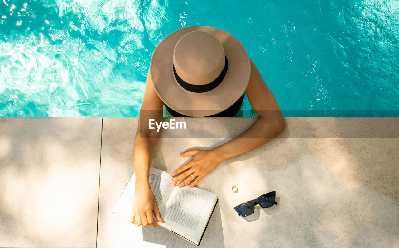 Young woman reading a book in the pool