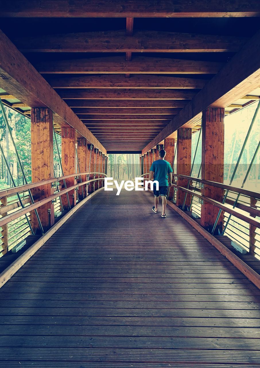 YOUNG WOMAN WALKING ON FOOTBRIDGE