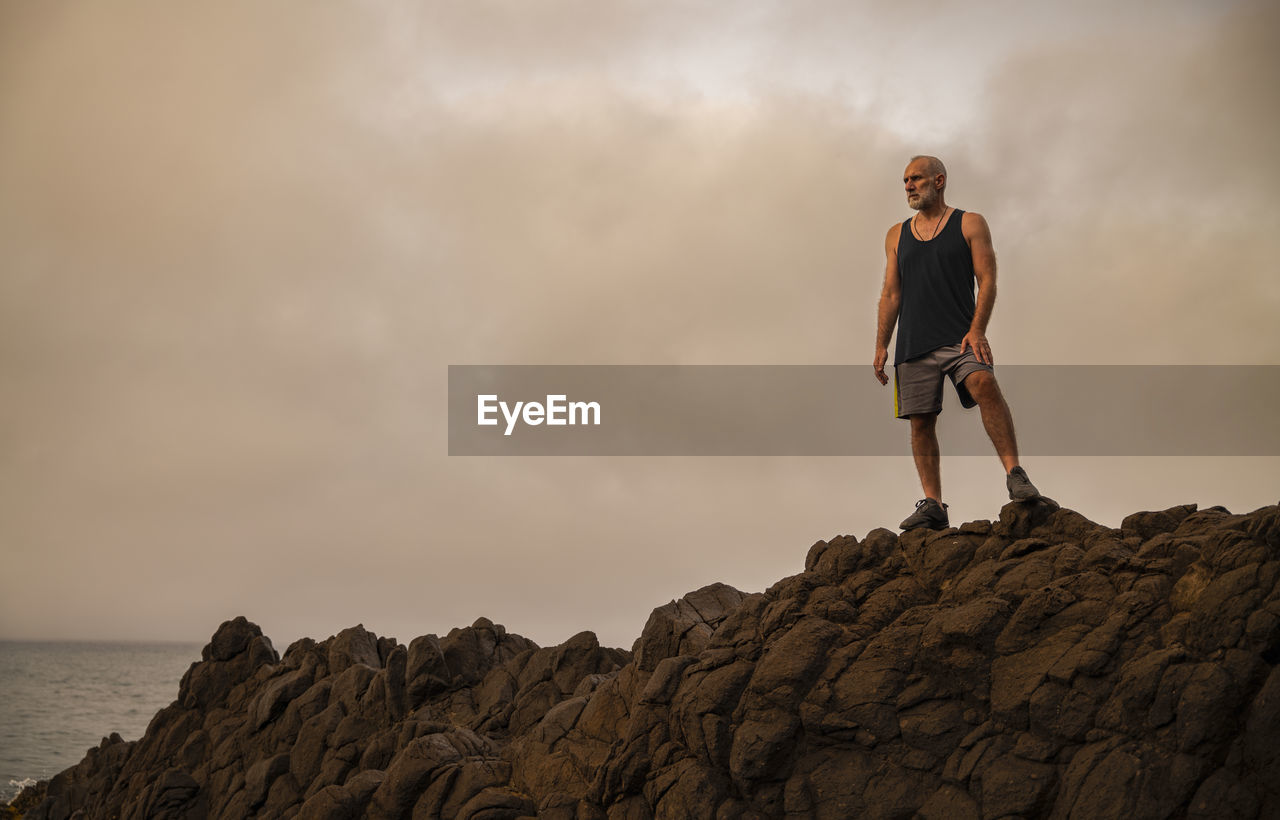 Man standing on rock against sky