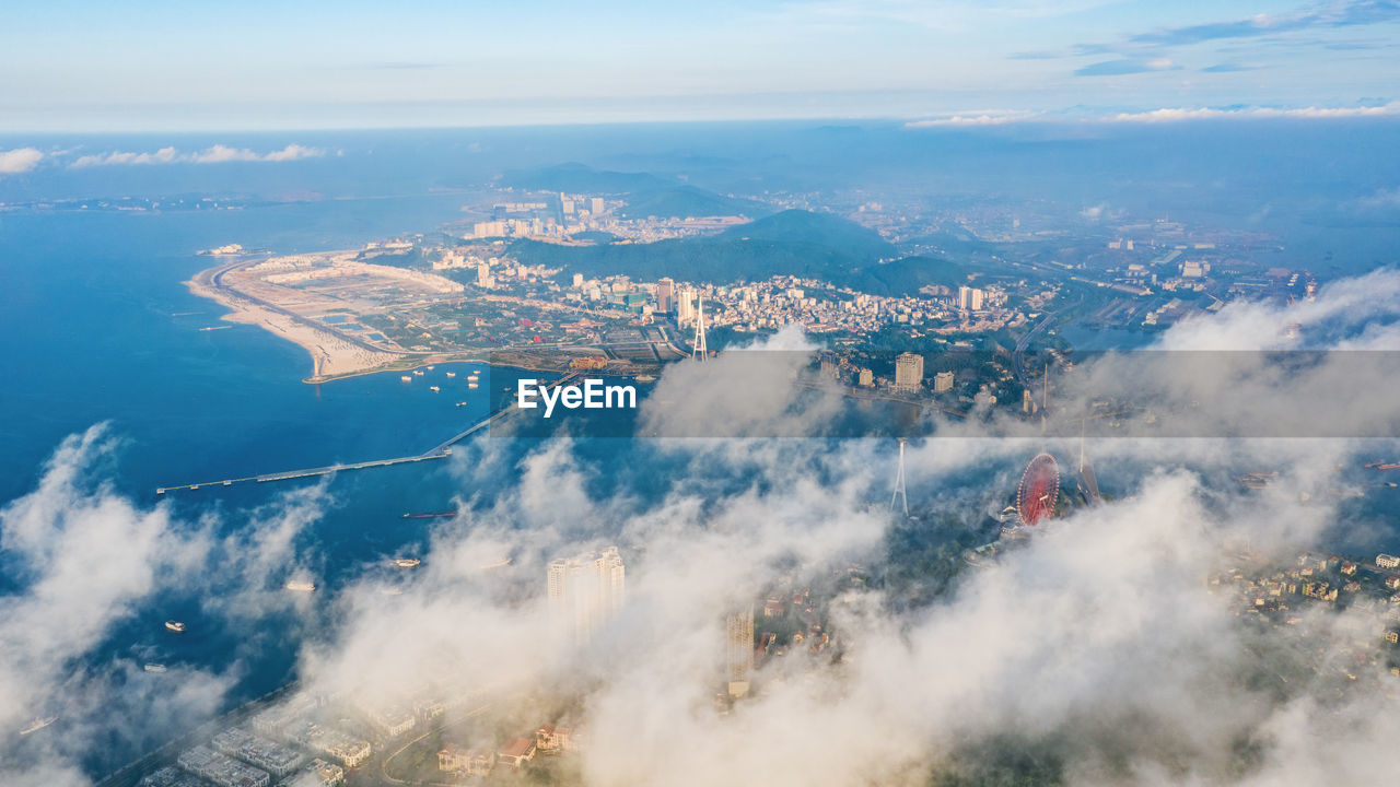 Aerial view of city by sea against sky