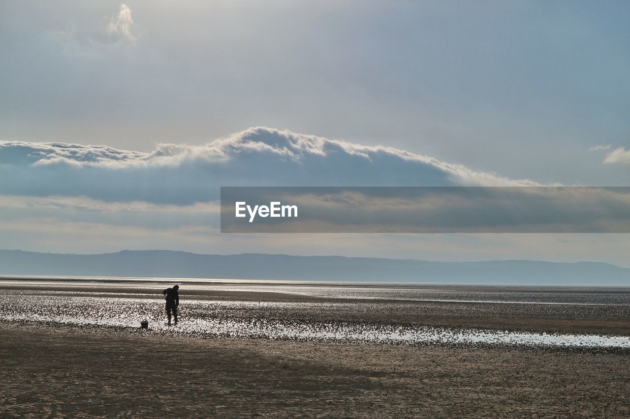 Man standing on salt flat against sky