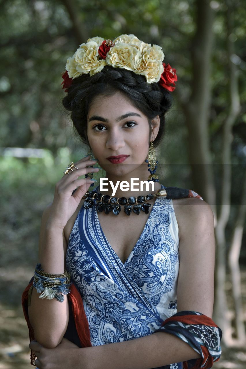 Portrait of young woman wearing tiara and dress standing in park