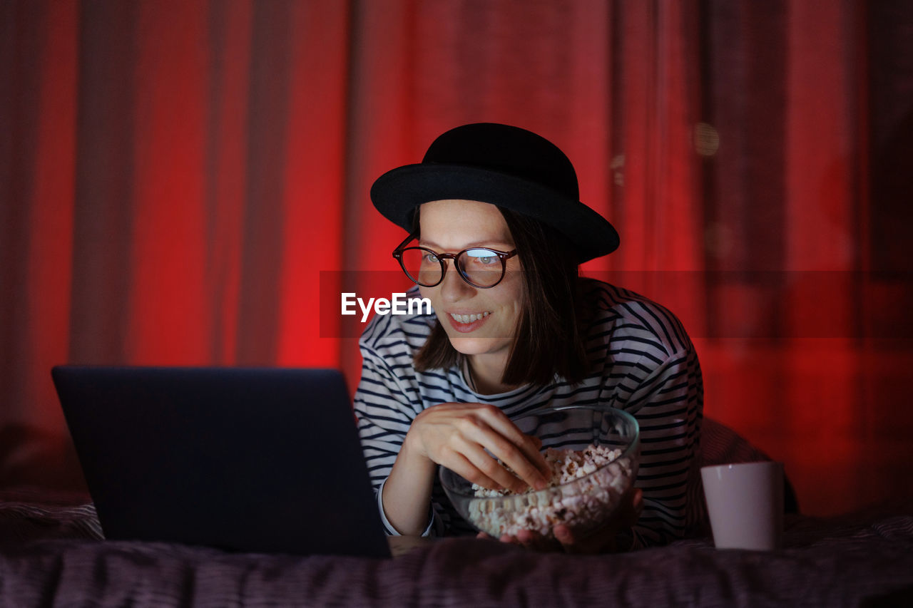 young woman using mobile phone while sitting on sofa at home