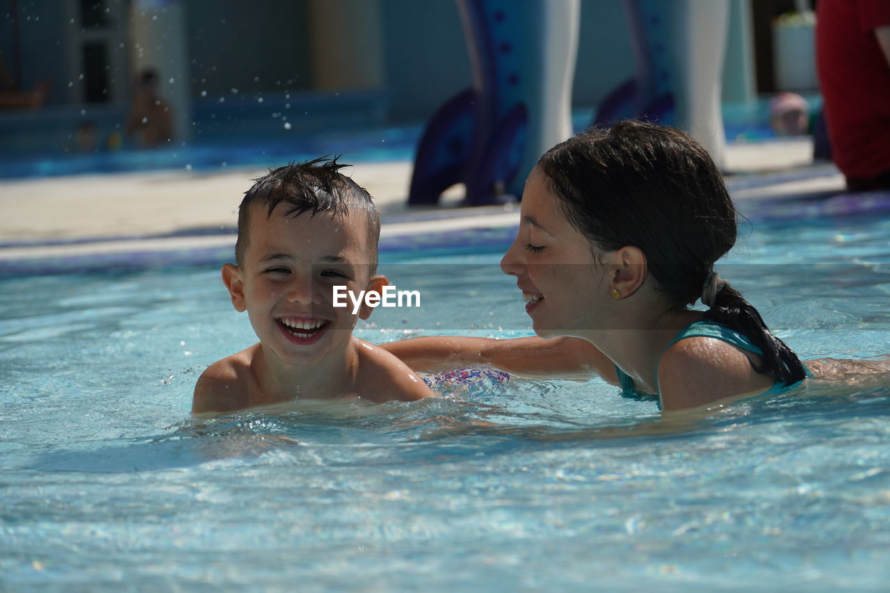 Portrait of happy brother with sister swimming in pool