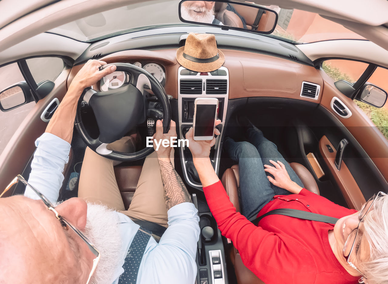 High angle view of couple looking at smart phone in car