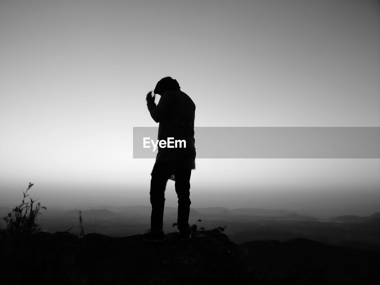 Silhouette man standing on rock against clear sky