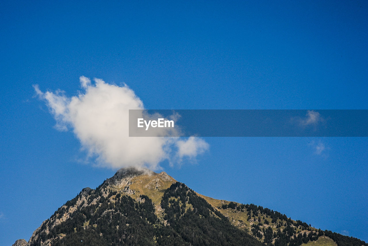 LOW ANGLE VIEW OF SMOKE ON MOUNTAIN AGAINST SKY