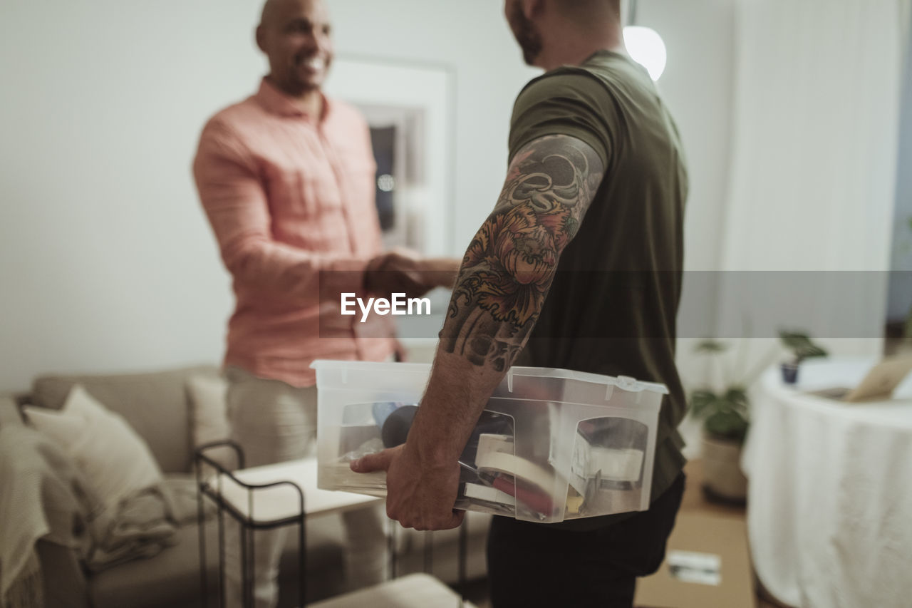 Male craftsperson holding toolbox while doing handshake with customer at home