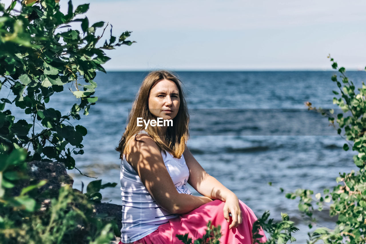 A pregnant woman is sitting on the beach