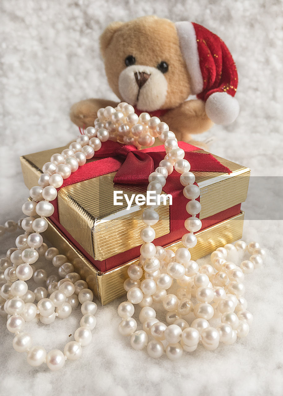 Close-up of stuffed toy and pearl necklace with christmas present