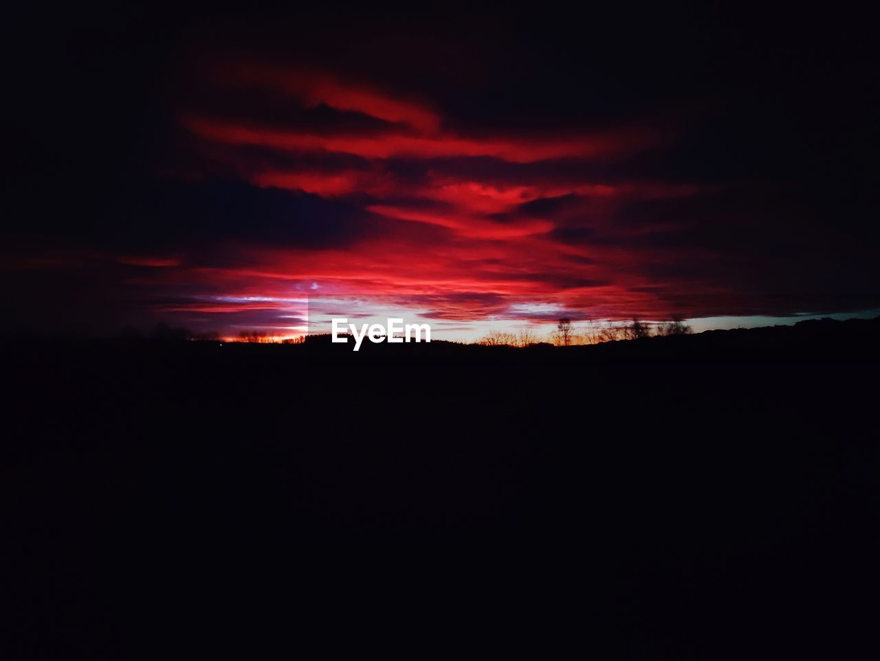 SILHOUETTE OF LANDSCAPE AGAINST DRAMATIC SKY