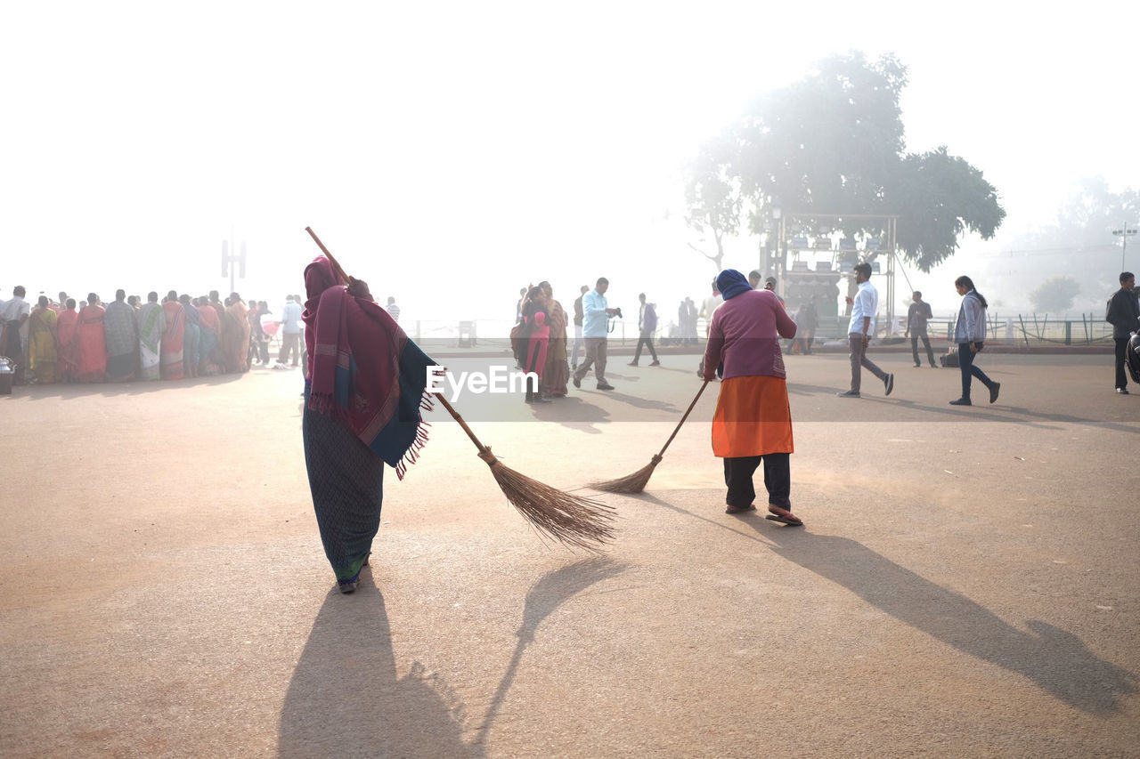 Women sweeping street in city