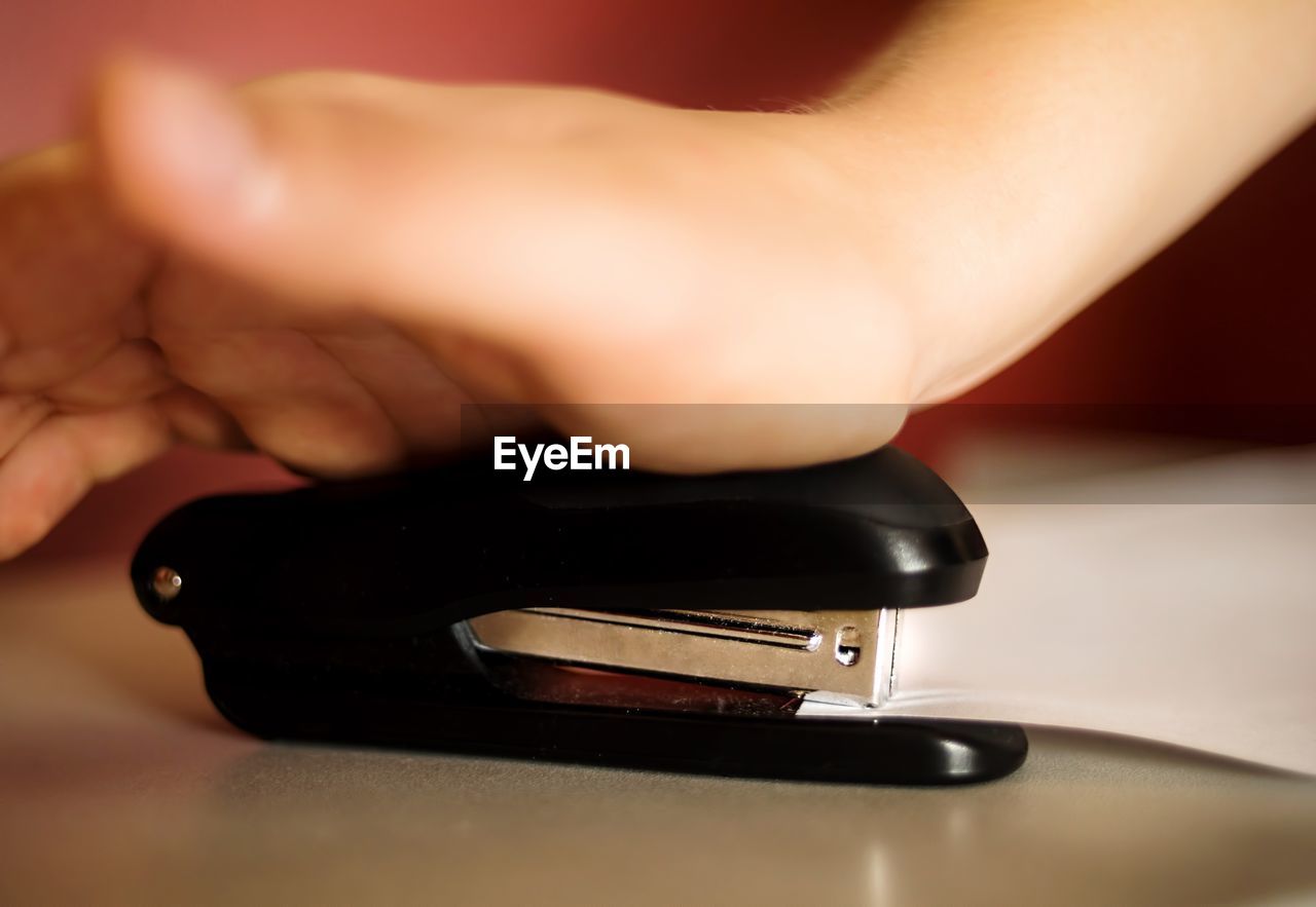 Cropped hand stapling paper on desk