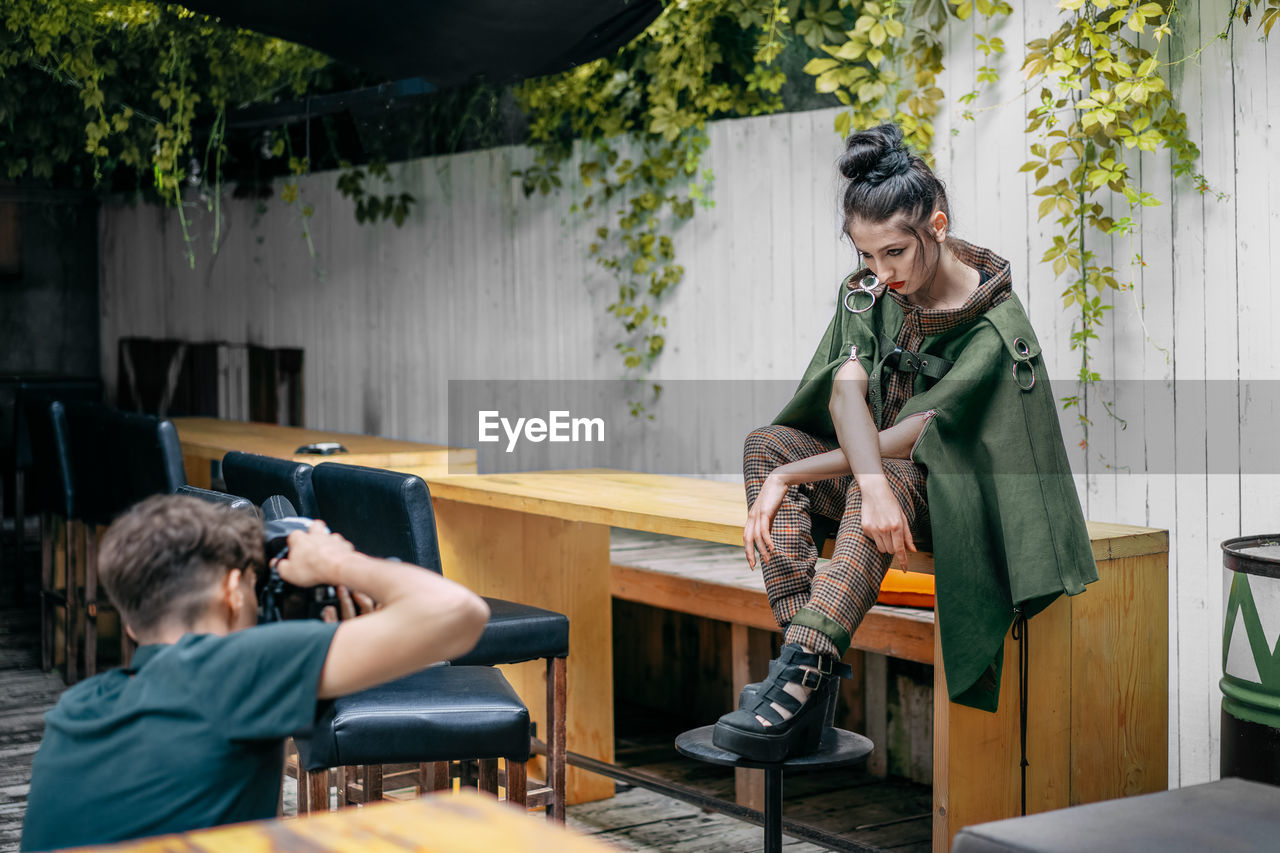 Man photographing woman sitting on table