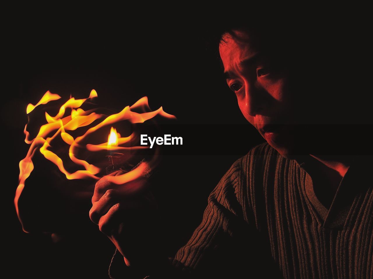 Close-up of man holding cigarette lighter against black background