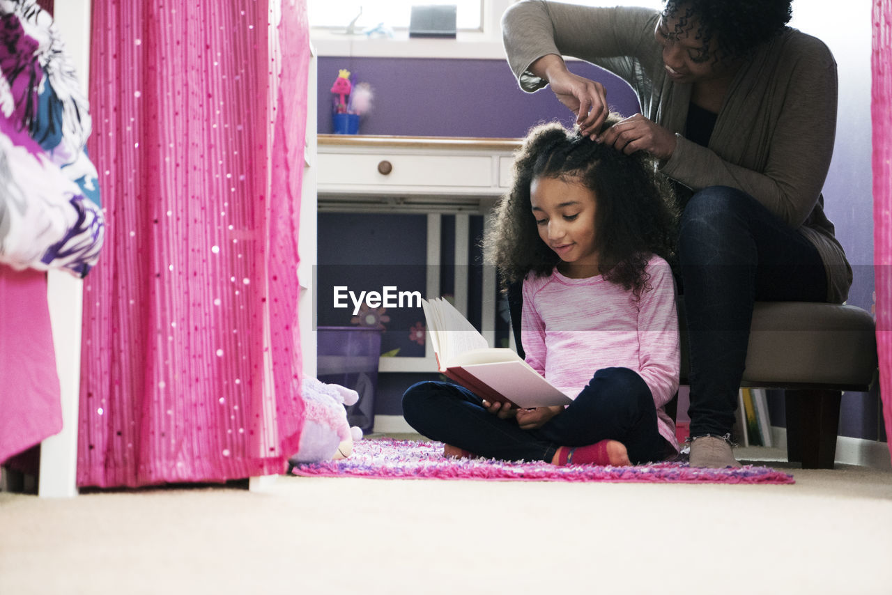 Woman combing daughter's hair at home