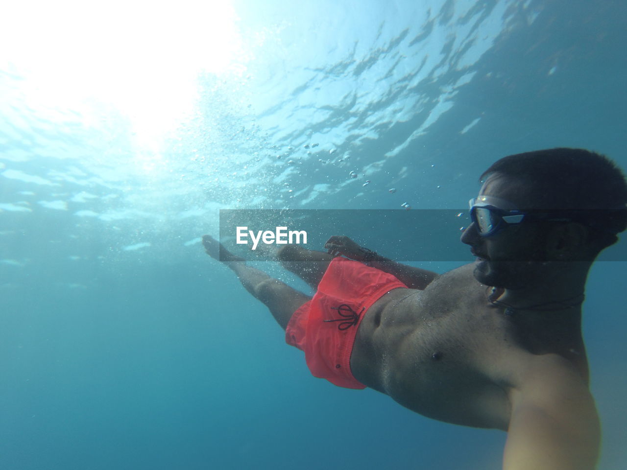 MAN SWIMMING IN SEA AGAINST BLUE SKY